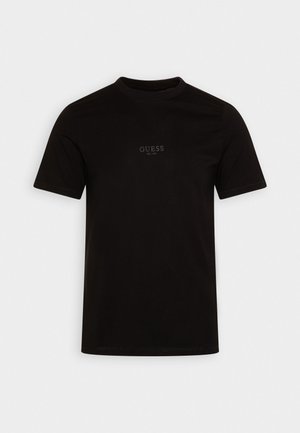 Must rõngaste varrukatega T-särk, mis on valmistatud puuvillast. Särk on ümmarguse kaelusega ja selle esiküljel on logo, millel on peene disainiga kiri "GUESS EST. 1981".