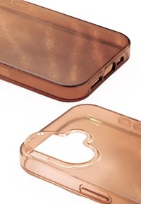 Przezroczyste brązowe etui na telefon o błyszczącej fakturze, zaokrąglonych rogach, wycięciu na aparat w kształcie serca oraz zielonym napisie "IDEAL OF SWEDEN".