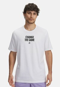 Camiseta de algodón blanca con la frase "CAMBIA LAS REGLAS" impresa en negrita en negro. Mangas cortas y un ajuste relajado.
