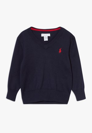 Granatowy sweter z dzianiny z dekoltem w serek, z czerwonymi akcentami na kołnierzu oraz małym czerwonym logo na lewej piersi.