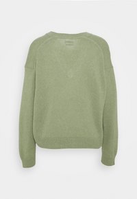 Zielony sweter z dzianiny o luźnej sylwetce, z ribbowanymi mankietami i dołem oraz miękką teksturą. Posiada okrągły dekolt i rękawy raglanowe.