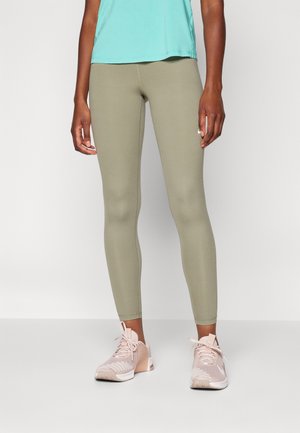 Leggings verde oliva hechos de tejido elástico, diseño ajustado. Combinados con zapatillas deportivas rosa claro que presentan detalles texturizados y cordones.