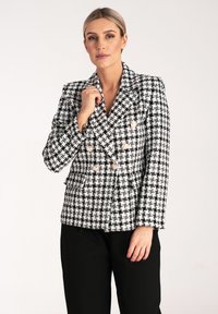 Dwurzędowa marynarka z mieszanki wełny w czarno-białą kratę houndstooth, z dużymi kremowymi guzikami i dwoma przednimi kieszeniami. Dopasowany krój.