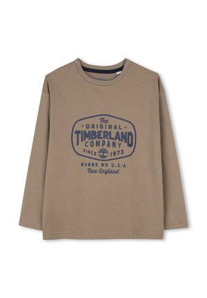 Chemise marron à manches longues avec logo Timberland bleu foncé et texte "The Original Timberland Company Since 1973 New England USA."