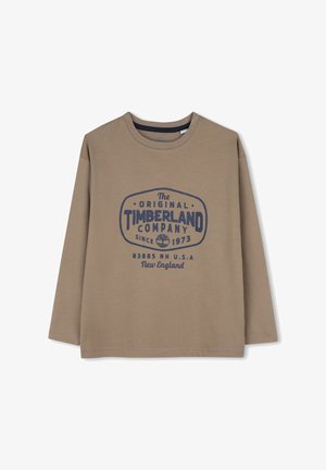 Chemise marron à manches longues avec logo Timberland bleu foncé et texte "The Original Timberland Company Since 1973 New England USA."