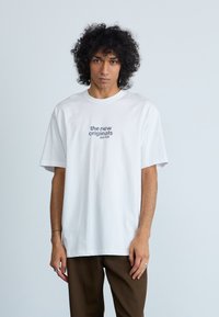 Vit bomulls t-shirt med korta ärmar, rundad halsringning, med texten på framsidan: "the new originals jazz club," enkel, avslappnad passform.