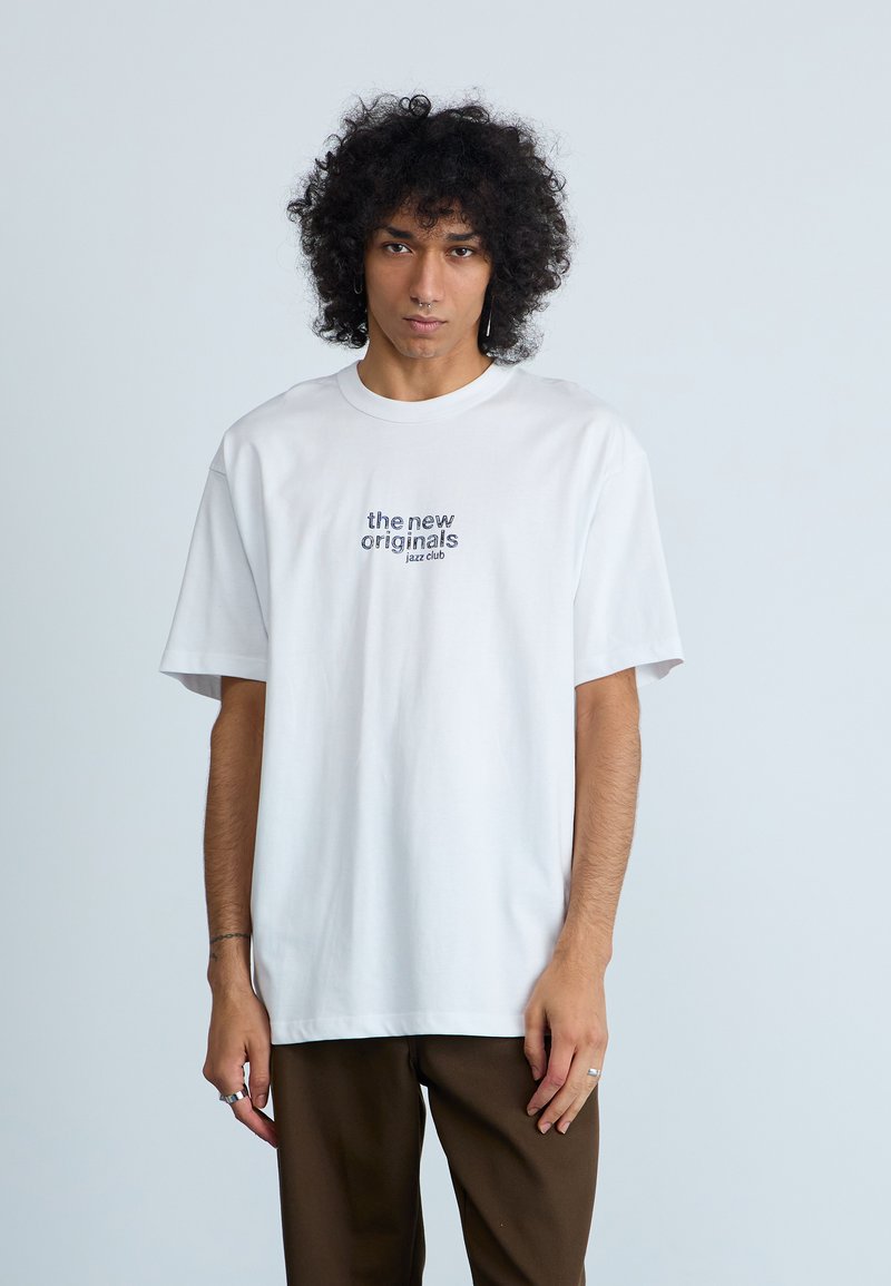 Vit bomulls t-shirt med korta ärmar, rundad halsringning, med texten på framsidan: "the new originals jazz club," enkel, avslappnad passform.