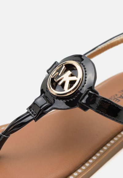 Svarta lackläder sandaler med en guldsymbol, med platt sula, beige inläggssula och en delikat remdesign.