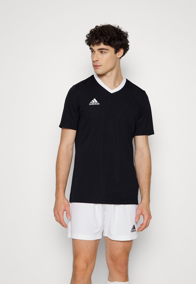 Svart idrottströja med vit V-ringning, med en Adidas-logotyp på vänster bröst. Mjuk tyg och korta ärmar.