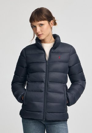 Marine pufferjack met ritsluiting, hoge kraag en geribde manchetten. Beschikt over gestikte horizontale panelen en een klein rood logo op de borst.