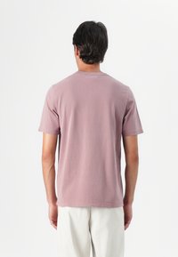 Short-sleeve, crew-neck t-shirt in soft pink fabric. Features a relaxed fit with visible stitching and a smooth texture. Plain back view.