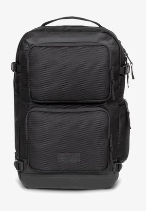 Musta reppu, joka on valmistettu teksturoituneesta nailonista ja jossa on kaksi etupuolen vetoketjullista taskua, pehmustetut hihnat ja vahvistettu kahva ylhäällä.