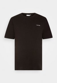 Svart bomulls t-shirt med rundad halsringning, kort ärm och en liten vit Calvin Klein-logotyp på vänster bröst. Slät yta.
