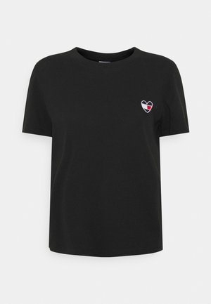 Schwarzes T-Shirt mit kurzen Ärmeln und kleinem, gesticktem Herzpatch in Weiß, Rot und Schwarz auf der linken Brust.