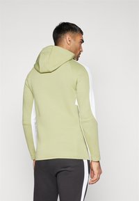 Hoodie in lichtgroen en wit, met een fitted ontwerp, lange mouwen en contrasterende zijaccenten. Zachte stoftextuur.