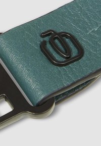 Portachiavi in pelle verde texturizzata con un logo rettangolare in rilievo nero e un portachiavi metallico attaccato.