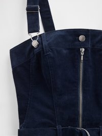 Σκούρο μπλε ολόσωμη φόρμα από κοτλέ με ρυθμιζόμενους ιμάντες, εμπρόσθιο φερμουάρ και ασημένιες λεπτομέρειες. Μαλακή υφή με δομημένο σχέδιο.