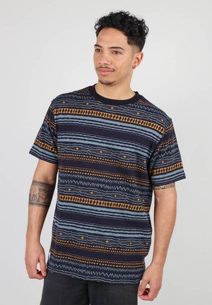T-shirt à manches courtes, col rond en marine foncé avec des motifs géométriques en teal et orange brûlé. Tissu lisse avec une coupe décontractée.