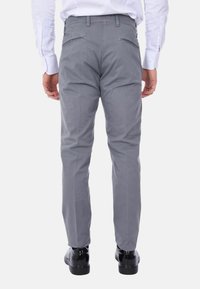 Pantaloni grigi realizzati in un tessuto liscio, con tasche posteriori e una vestibilità slim, abbinati a scarpe nere lucide.