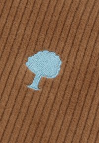Icono de árbol bordado en azul claro sobre un fondo de tela texturizada con costillas en color marrón.