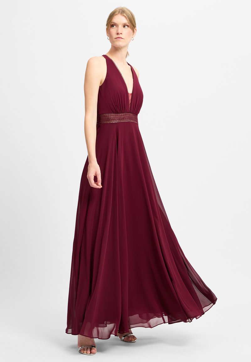 Burgunderfarbendes Maxikleid mit tiefem V-Ausschnitt, strukturiertem Taillenbund und fließendem Chiffonstoff. Verfügbar mit dünnen Trägern und einer glatten, drapierten Silhouette.