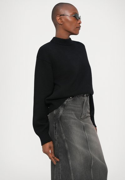 Pulover negru, din tricot, cu guler înalt, asortat cu o fustă din denim gri, cu cusături verticale și o siluetă dreaptă.