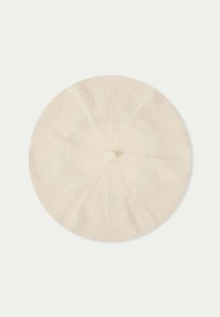 Krämfärgad basker i mjukt tyg, rund form med en centrerad knapp, med åtta sektioner i en jämn textur.