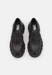 Mocassins en cuir noir avec une tige texturée arborant un détail de logo. Semelle extérieure épaisse en caoutchouc pour plus de traction. Intérieur doublé pour le confort.