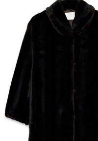 Zwarte lange jas van nepbont met brede kraag en knoopsluiting, gepresenteerd tegen een witte achtergrond.