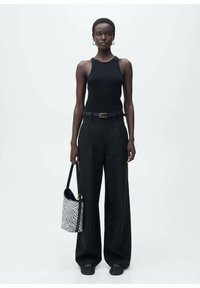 Top nero senza maniche, pantaloni neri a vita alta, scarpe piatte intrecciate e una borsa a zebre, con una vestibilità elegante e una texture sottile.