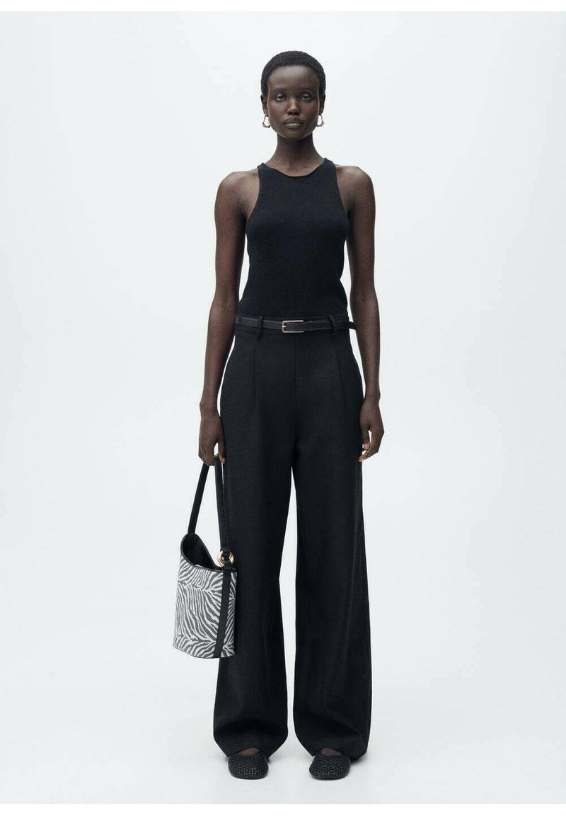 Top nero senza maniche, pantaloni neri a vita alta, scarpe piatte intrecciate e una borsa a zebre, con una vestibilità elegante e una texture sottile.