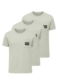 Tres camisetas de algodón verde claro con mangas cortas. Cada una cuenta con un bolsillo en el pecho con detalles en etiqueta negra. Diseño simple y sólido.