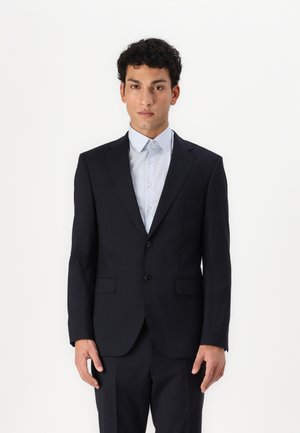 Marineblazer, einreihig, mit zwei vorderen Taschen, kombiniert mit einem hellblauen gestreiften Hemd. Der Stoff erscheint glatt und hat eine taillierte Passform.