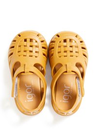 Sandales en caoutchouc jaune avec un design tissé, bouts fermés, côtés ouverts, une sangle au talon et un logo imprimé sur les semelles intérieures.