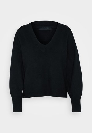 Pull noir à col en V avec une coupe ample, manches longues et poignets côtelés. Fabriqué en tissu doux et texturé, avec une longueur courte.