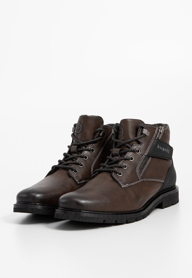 Botas de cuero marrón hasta el tobillo con acentos negros, puntera redonda y diseño con cordones. Presentan un cierre de cremallera y detalles de costura en contraste.