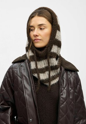 Brun quiltet jakke over en mørk sweater, prydet med et stribet uldscarf i brun og grå med to hængende bånd.