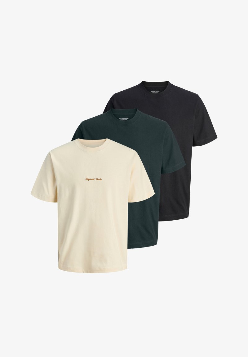 Trois t-shirts unis à col rond en crème, vert foncé et noir, avec un petit texte "Original Studio" au centre avant du t-shirt crème.
