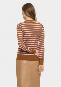 Braun und hellrosa gestreifter Strickpullover mit langen Ärmeln und rundem Halsausschnitt, kombiniert mit einem hellbraunen Lederrock.
