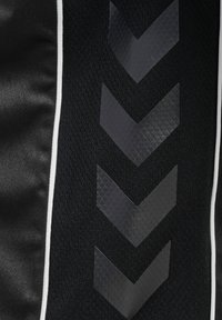Czarna materiał sportowy o teksturowanym wzorze, z trzema wyraźnymi szarymi kształtami chevron i białą lamówką wzdłuż krawędzi.