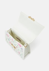 Valkoinen nahkainen käsilaukku, jossa on kukkakuvio ja kullanvärinen lukko. Laukussa on tilava, vuoraamaton sisäosa ja jämäkkä muoto.