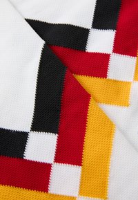 Tecido de malha com um padrão geométrico de quadrados vermelhos, pretos, amarelos e brancos. Superfície texturizada com detalhes de costura contrastantes.