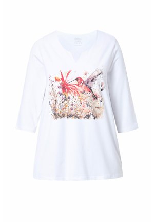 Haut en coton blanc avec un col en V et des manches trois-quarts. Présente un motif floral coloré et des colibris sur le devant.