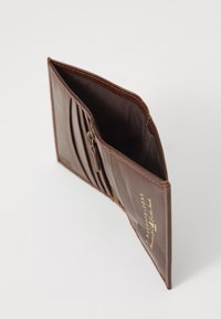 Brown leather wallet, featuring a zippered compartment and pleated design. Interior shows a smooth fabric lining with embossed branding.