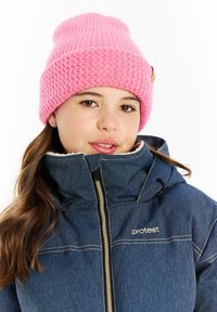 Roze gebreide muts met een textuurpatroon, gecombineerd met een blauwe spijkerjack met een bontgevoerd kraag en een ritssluiting.