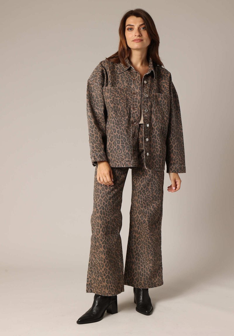 Veste en jean imprimée léopard et pantalon évasé assorti dans des tons terreux. Tissu texturé avec deux poches sur la veste et une coupe ajustée.