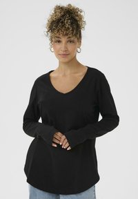 Zwarte lange mouw V-hals top met een relaxed fit, voorzien van een verlengde zoom en duimgaten in de manchetten. Gladde textuur, casual ontwerp.
