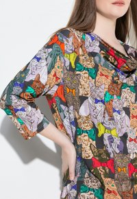 Colorful tunic featuring various illustrated cats wearing bowties in shades of orange, green, blue, purple, and red on a dark background.