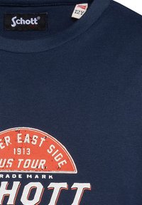 Camiseta de manga corta azul marino, con textura acanalada, que presenta un gráfico de estilo vintage en rojo y blanco con "Schott" y "East Side 1913 US Tour."