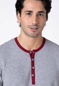 Maglietta henley grigia con colletto a coste color amaranto e patta con cinque bottoni. Il tessuto ha un motivo testurizzato.